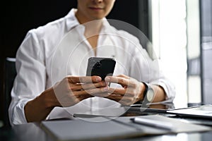 Close-up image of an Asian businessman sending sms to someone on his phone