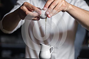 Close-up image of bartender hands breaking the egg into a milk p