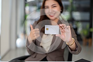 Close-up image of a beautiful Asian businesswoman or female banker showing a credit card