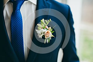 Close up image of beautiful boutonniere on the groom`s jacket. Soft focus on boutonniere. Artwork