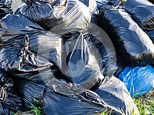 Close up image of big pile of waste in the black plastic bags, illegal garbage dump. The concept of ecology pollution