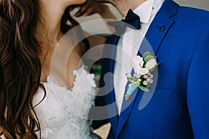 Close-up image of a Boutonniere on the groom`s jacket. Blurred bride and groom are kissing. Artwork