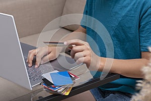 Close up image of boy`s hands holding credit card and pressing buttons on laptop during online payment. photo