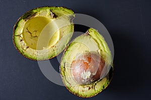 Close up image of a bruised and imperfect avocado on a black background- use these and avoid food waste