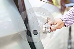 Close up image of a businessman hand on handle opening a car door.