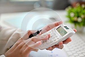 Close-up image of a businesswoman or female accountant using calculator, working at her desk