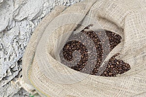 Close up image of canvas sack fuul of roasted brown coffee beans