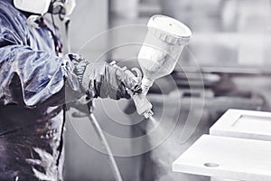 Close up image of carpenter painting with a paint spray gun