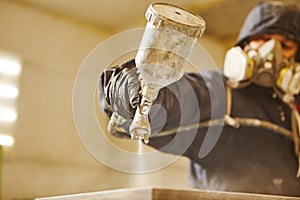 Close up image of carpenter painting with a paint spray gun