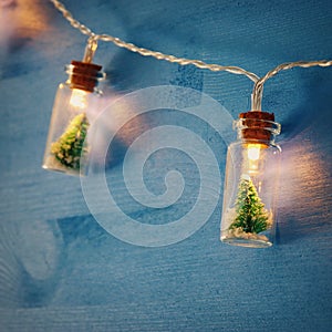 close up image of Christmas tree in the masson jar garland light over wooden blue background.