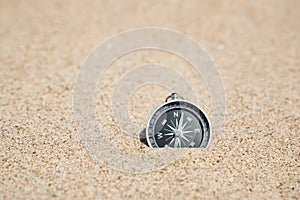 Close-up image of a compass on the sand. Copy space.