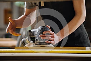 Close up image of a craftsman grinding a wooden plank. No head, cropped