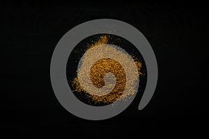 Close-up image of cumin powder on black wood background, view above