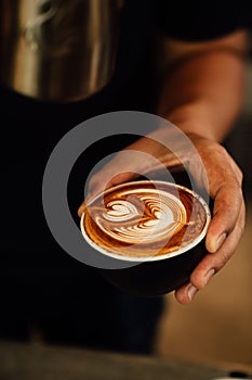 Close-up image of a cup of freshly brewed coffee with intricate latte art poured on top