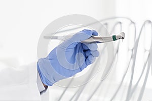 Close up image of dentist hand holding steel dental drill