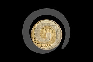 An old, gold coin from Yugoslavia isolated on a black background