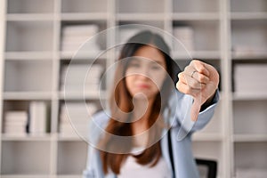 Close-up image of a dissatisfied and upset Asian businesswoman showing thumbs down dislike gesture