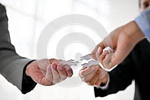 Close-up image of diverse businesspeople holding a piece of jigsaw puzzle