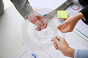 Close-up image of diverse businesspeople holding a piece of jigsaw puzzle