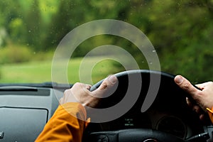 Close up image of Driver`s hands on steering wheel driving a modern off road right hand drive RHD car on the mountain green fores