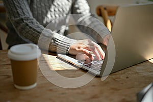 Close-up image of a female freelancer responding to emails, typing on her laptop keyboard