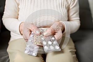 Close-up image of female hands holding pills. Senior woman following her treatment, taking care after health with