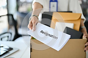 Close-up image of a female office worker handing a resignation letter, quitting job by herself