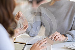 Close-up image of a female realtor giving a house key chain to new tenant