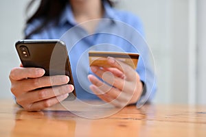 Close-up image, A female sitting at the desk, holding a smartphone and a credit card