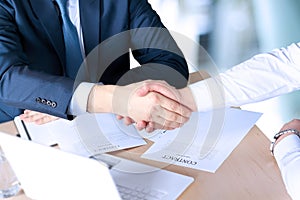 Close-up image of a firm handshake between two colleagues after signing a contract