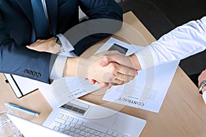 Close-up image of a firm handshake between two colleagues after signing a contract