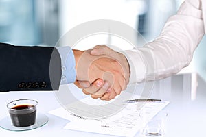 Close-up image of a firm handshake between two colleagues under
