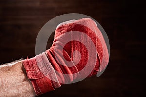 Close up image of fist of a boxer with red bandage against brown background.