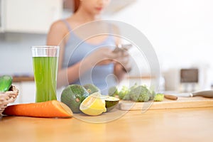 Close-up image of a glass of healthy green juice and fresh fruits and vegetables on a kitchen table