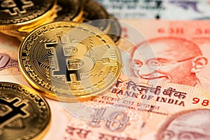 Close up image of gplden Bitcoin with Indian Rupee banknotes. Bitcoin on India Rupee Cryptocurrency against money from India