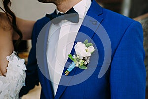 Close-up image of a groom in a blue tuxedo with White boutonniere. Boutonniere on the groom`s jacket. Artwork