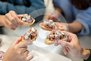 Close-up image of a group of friends enjoying eating food at an Italian restaurant together