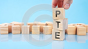 close up image hand of a young businessman holding a wooden cube with letter P. PTE on wooden cube on a blue background