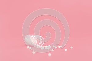 Close-up image of homeopathic globules in glass bottle on pastel pink background. Homeopathy pharmacy, herbal, natural