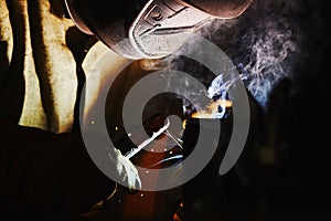 Close-up image of industrial worker at the factory welding steel structure on black background.