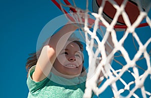 Close up image of kid basketball player making slam dunk during basketball game, stock photo. Banner isolated on sky