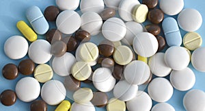 Close up image of a lot of different medical pills, capcules, tablets on blue background.