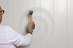 Close-up image of a male construction worker with a hammer skillfully tapping a nail into a wall