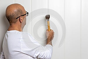 Close-up image of a male construction worker with a hammer skillfully tapping a nail into a wall