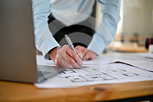 Close-up image of a male engineer checking scale and building plan design on a blueprint