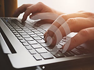 Close up image of male hands typing on laptop keyboard