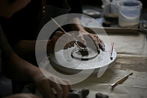 Close-up image of a man using a sculpting tool on raw clay to create shapes