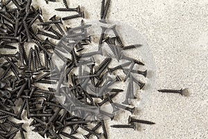 Close-up image of many small black screws on concrete background