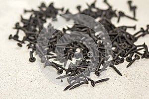Close-up image of many small black screws on concrete background