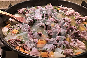 Close up image of meat with vegetables stewing in the pan with wooden spoon. Above view,